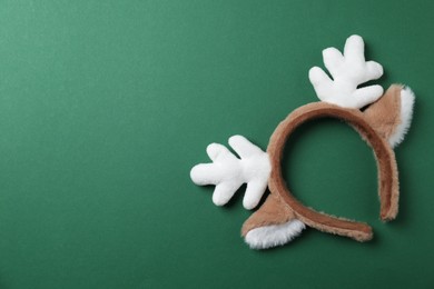 Photo of Beautiful reindeer headband on green background, top view with space for text. Christmas accessory