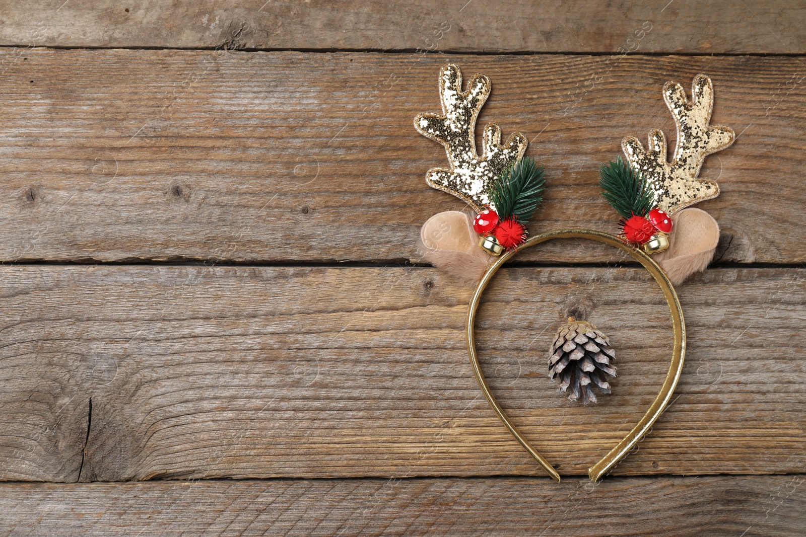 Photo of Beautiful reindeer headband and conifer cone on wooden background, top view with space for text. Christmas accessory