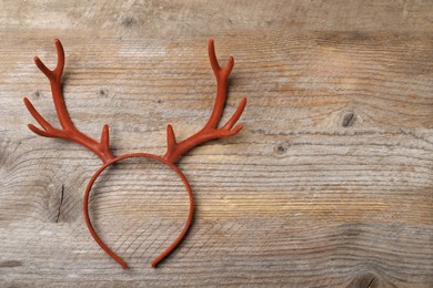 Photo of Beautiful reindeer headband on wooden background, top view with space for text. Christmas accessory