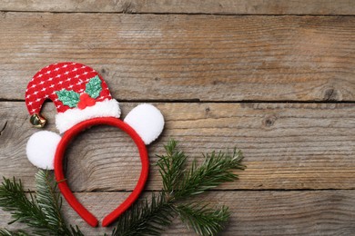 Photo of Stylish party headband and fir branches on wooden background, top view with space for text. Christmas accessory