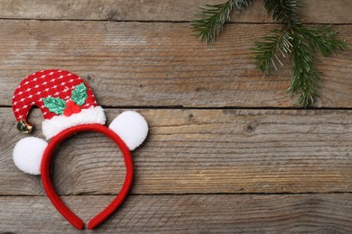 Photo of Stylish party headband and fir branch on wooden background, top view with space for text. Christmas accessory