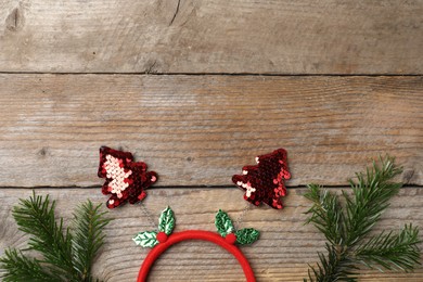 Photo of Stylish party headband and fir branches on wooden background, top view with space for text. Christmas accessory