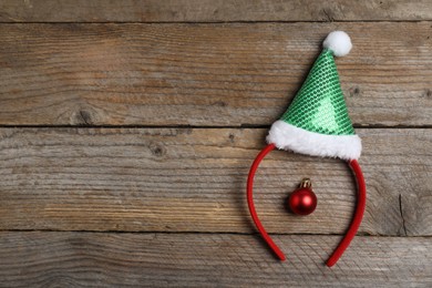 Photo of Stylish party headband and Christmas bauble on wooden background, top view. Space for text