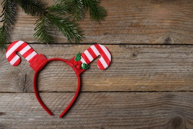 Photo of Stylish party headband and fir branch on wooden background, top view with space for text. Christmas accessory