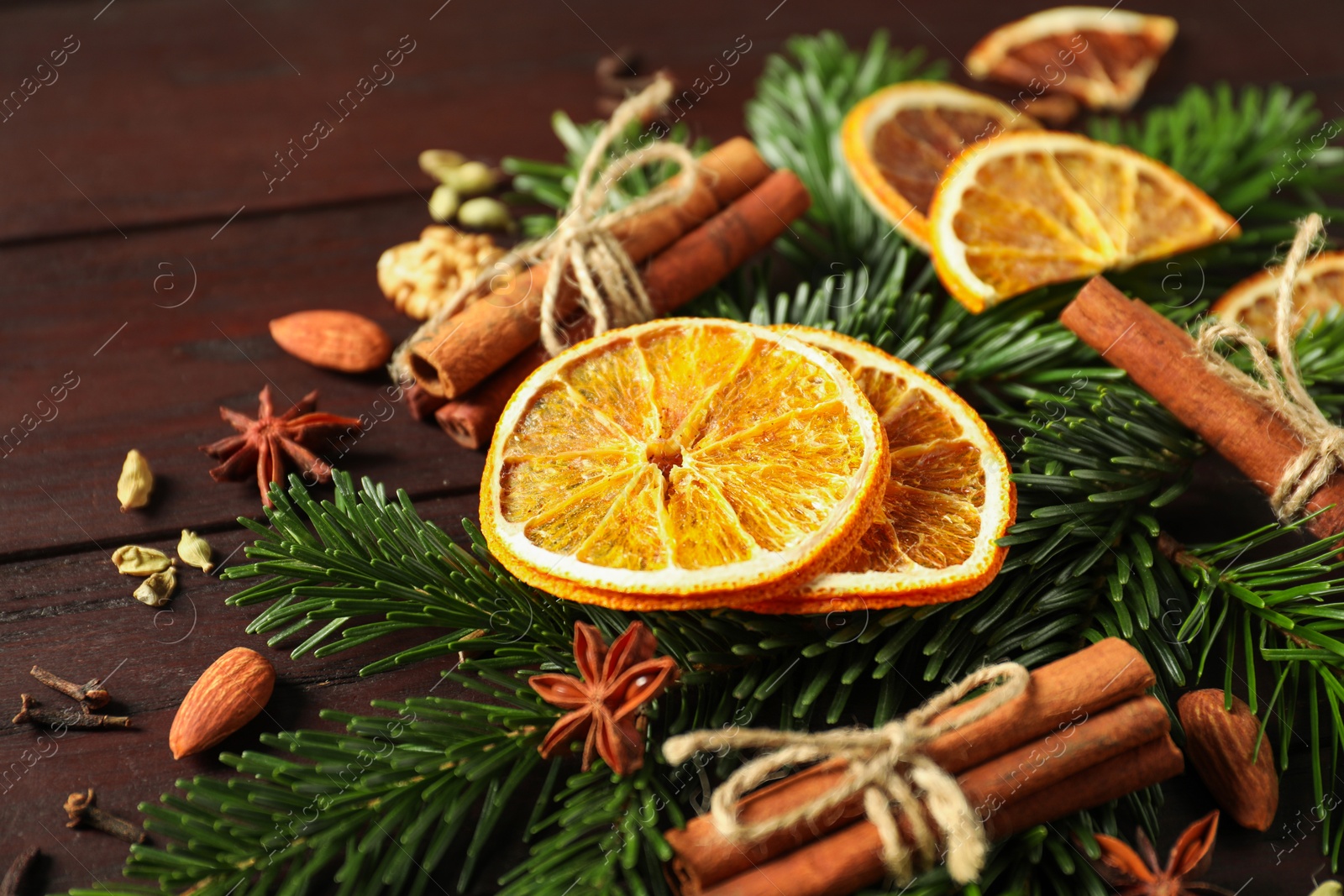 Photo of Different spices, dried orange slices and fir tree branches on wooden table, closeup. Christmas season