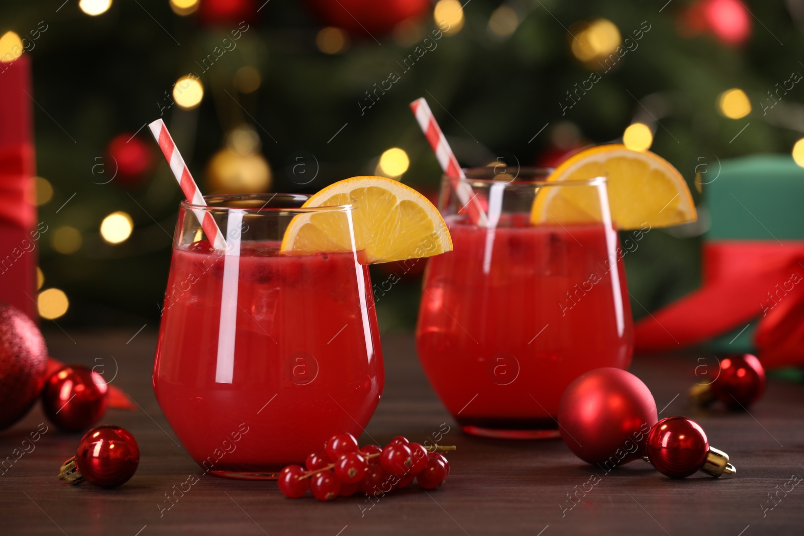 Photo of Christmas cocktail in glasses with lemon and currants on wooden table