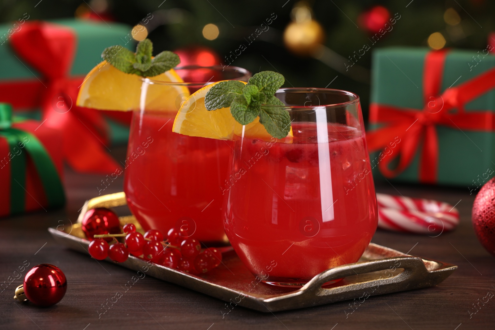 Photo of Christmas cocktail in glasses with lemon and currants on wooden table, closeup