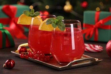 Photo of Christmas cocktail in glasses with lemon and currants on wooden table, closeup