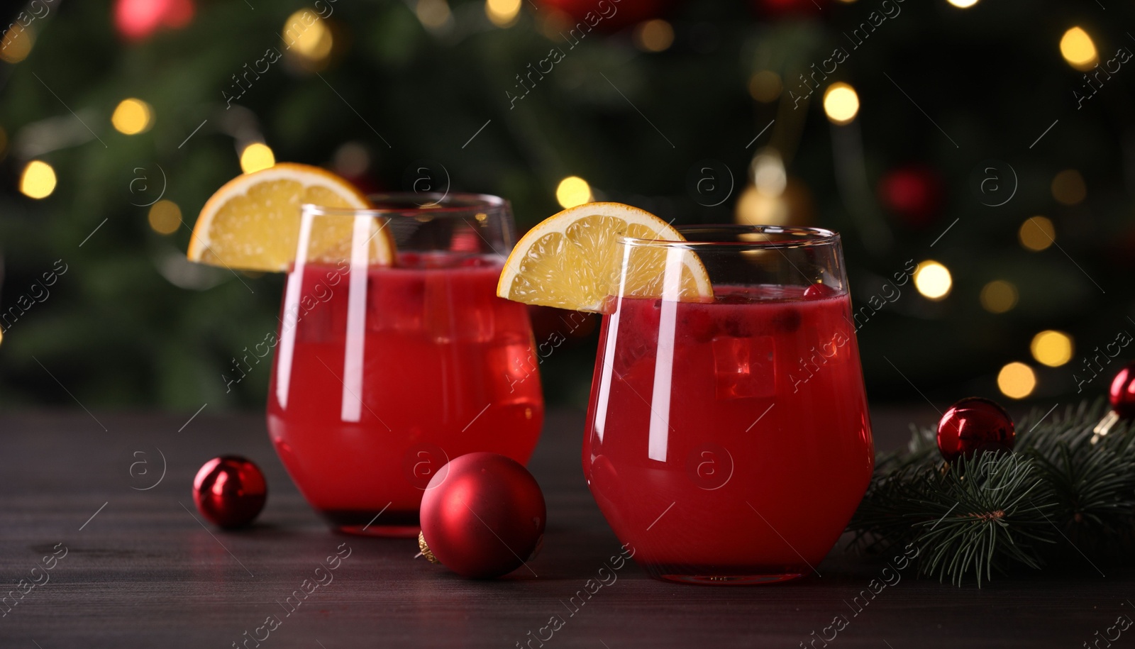 Photo of Christmas cocktail in glasses with lemon and decor on wooden table, closeup