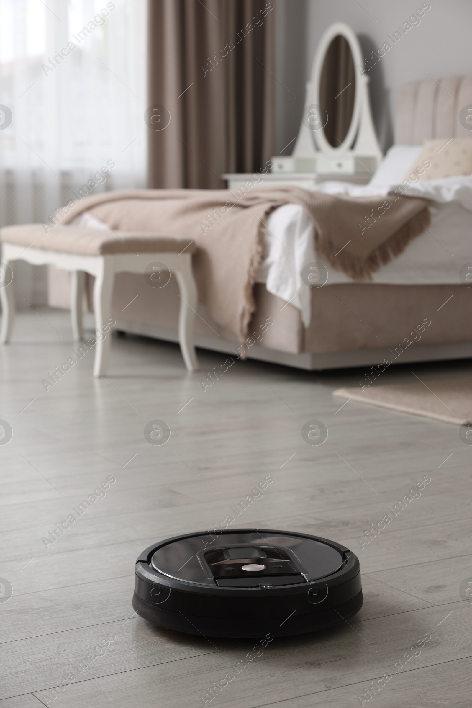 Photo of Robotic vacuum cleaner on wooden floor in bedroom