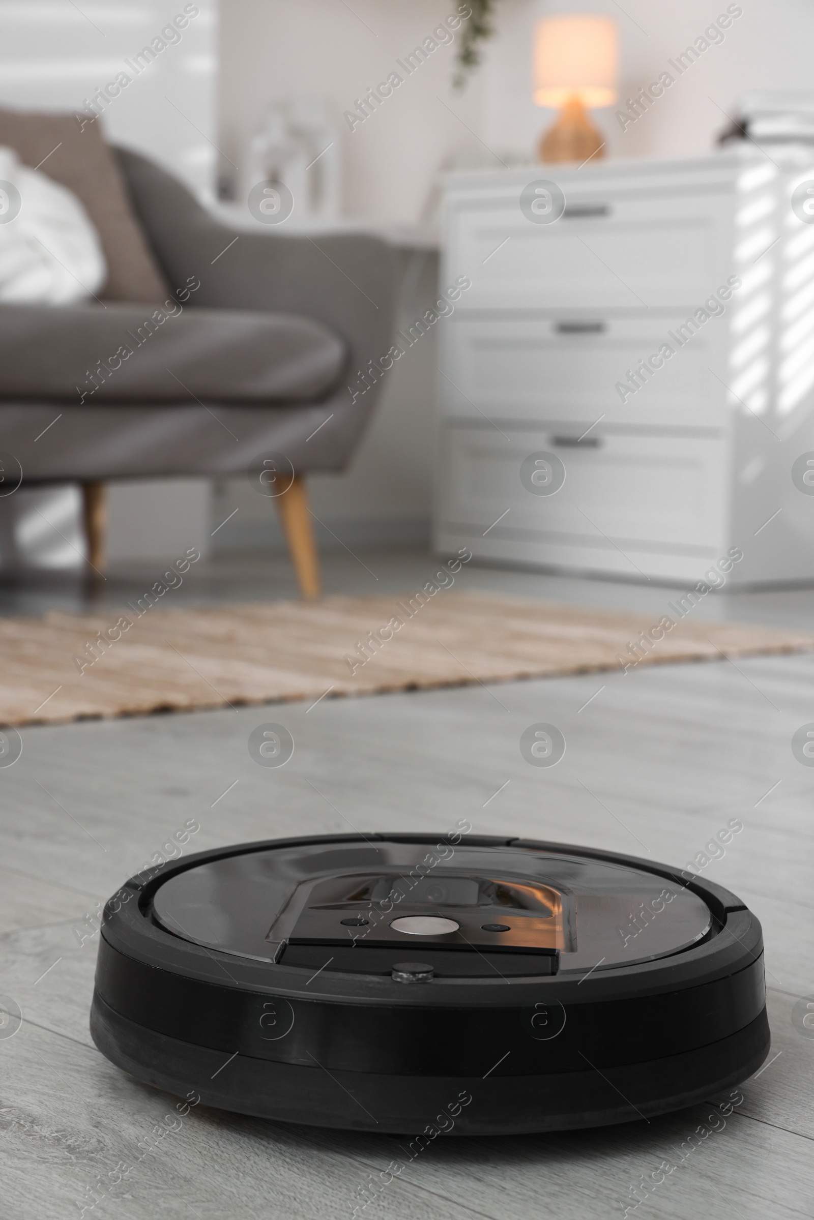 Photo of Robotic vacuum cleaner on wooden floor in living room