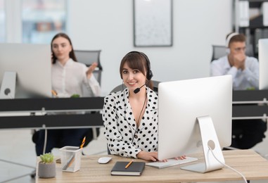 Photo of Saleswoman talking to client via headset at desk in office