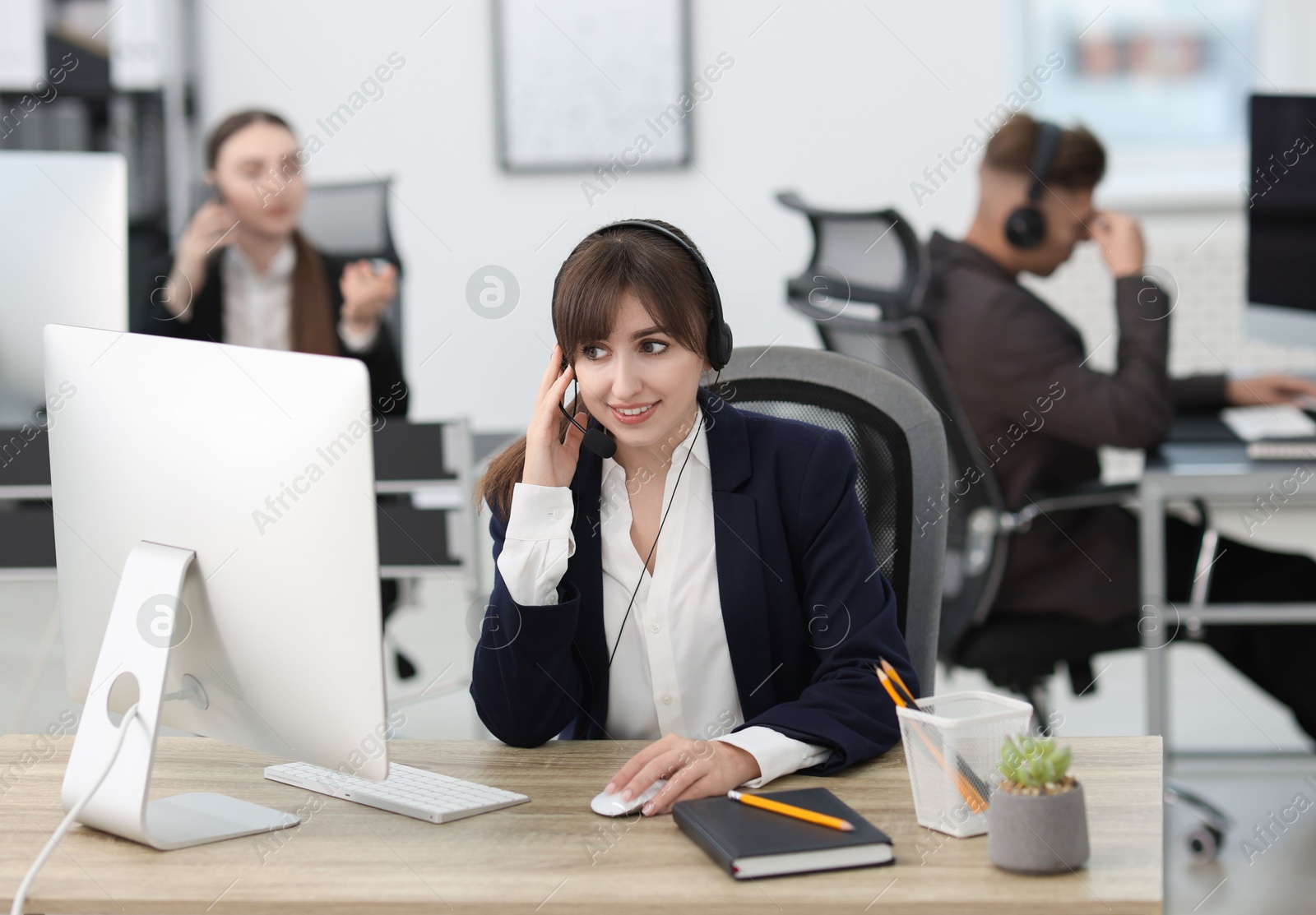 Photo of Saleswoman talking to client via headset at desk in office