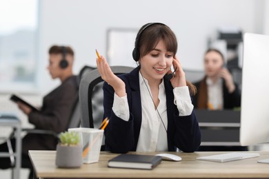 Photo of Saleswoman talking to client via headset at desk in office