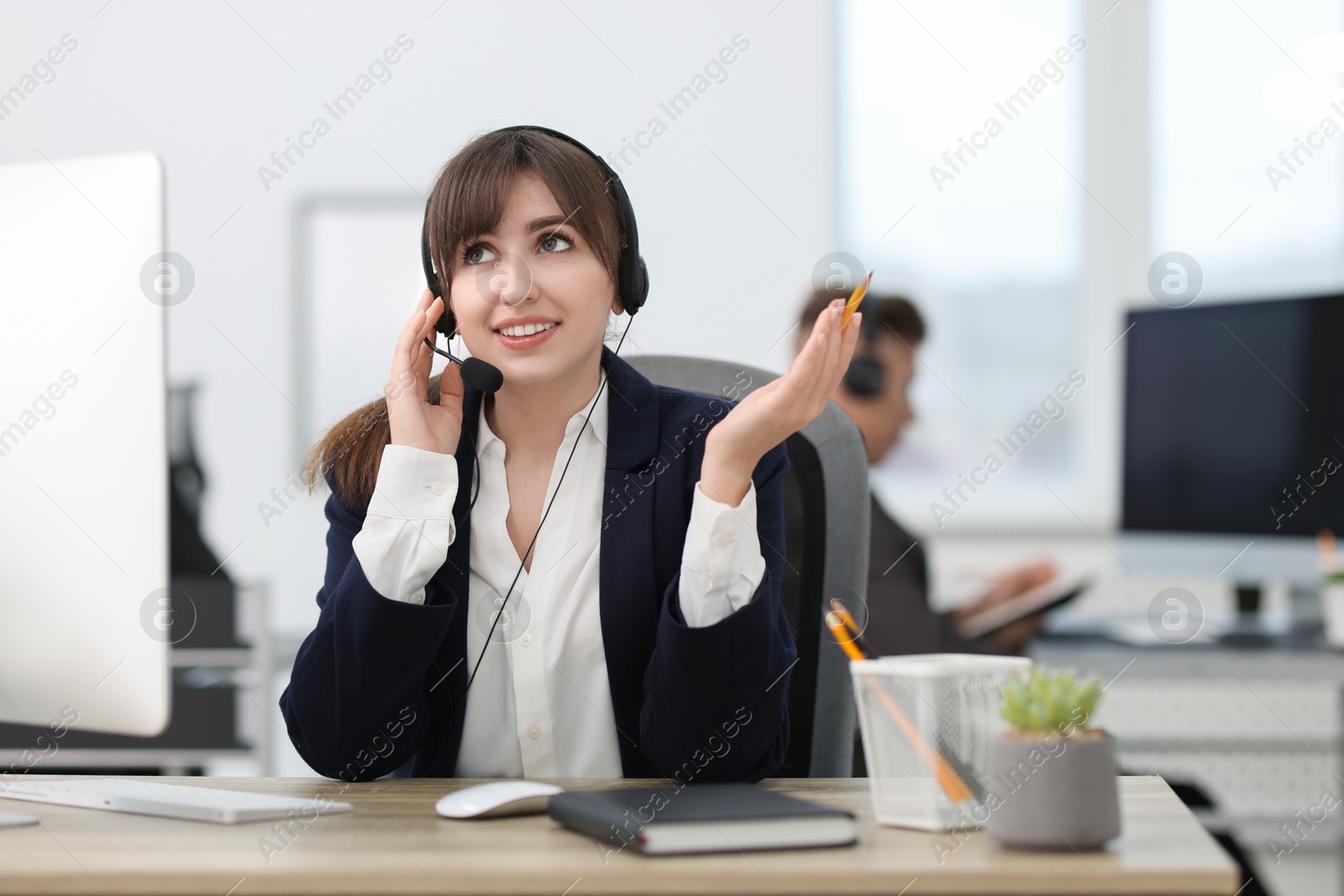 Photo of Saleswoman talking to client via headset at desk in office