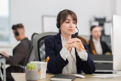 Photo of Saleswoman talking to client via headset at desk in office