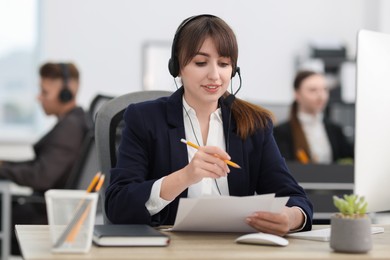 Photo of Saleswoman talking to client via headset at desk in office