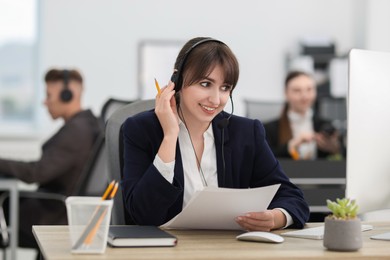 Photo of Saleswoman talking to client via headset at desk in office