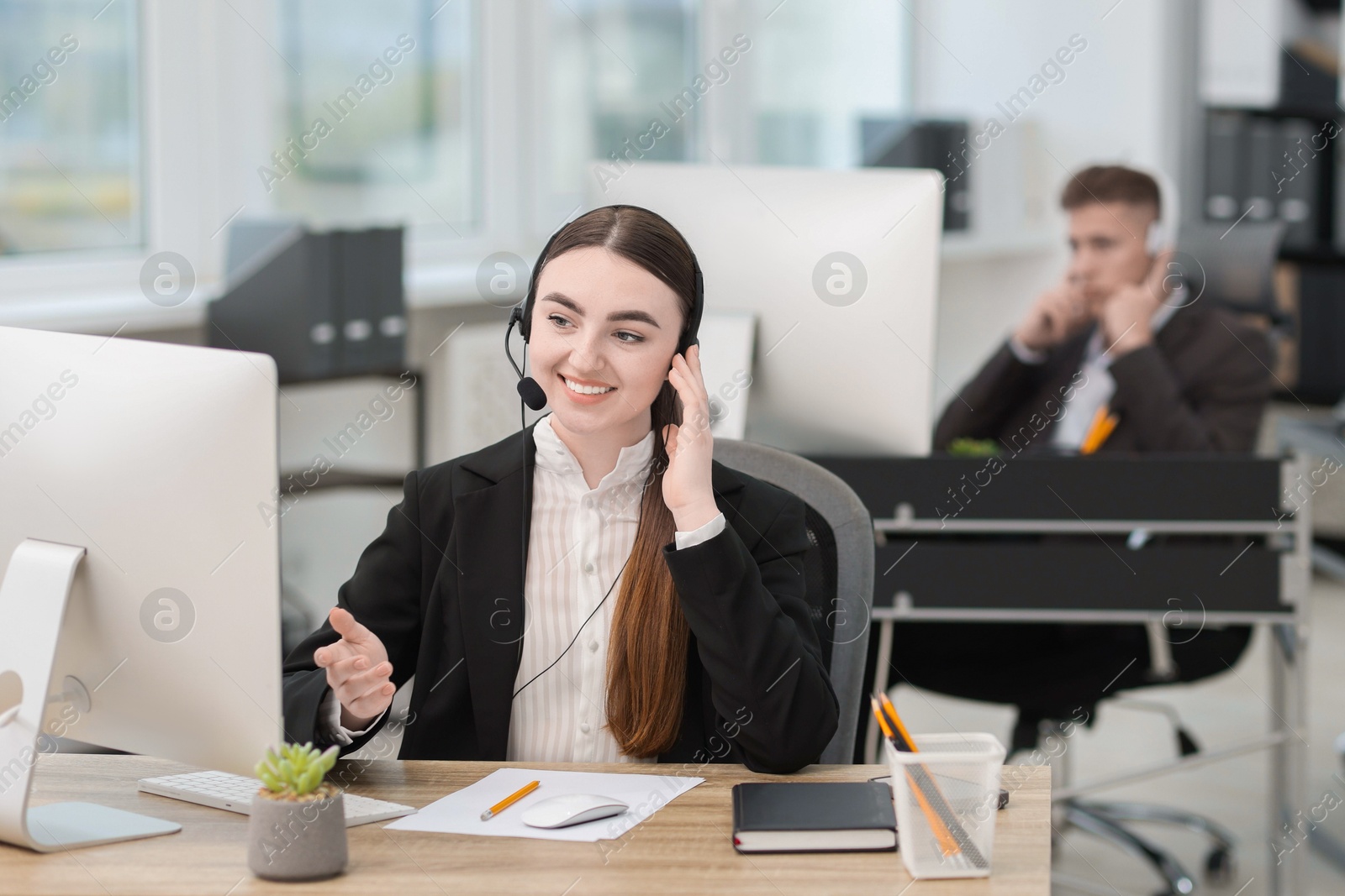 Photo of Saleswoman talking to client via headset at desk in office