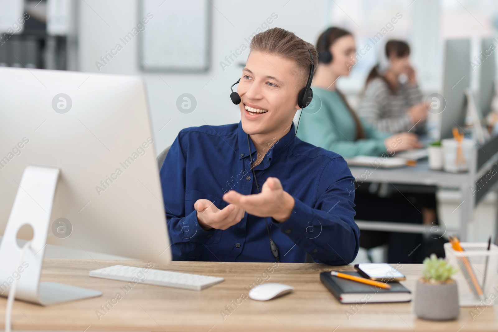 Photo of Salesman talking to client via headset at desk in office