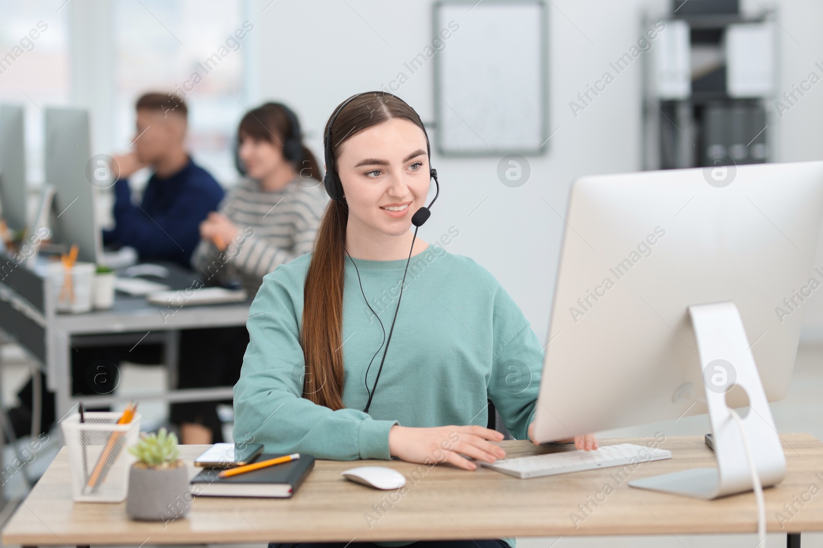 Photo of Saleswoman talking to client via headset at desk in office