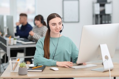 Photo of Saleswoman talking to client via headset at desk in office