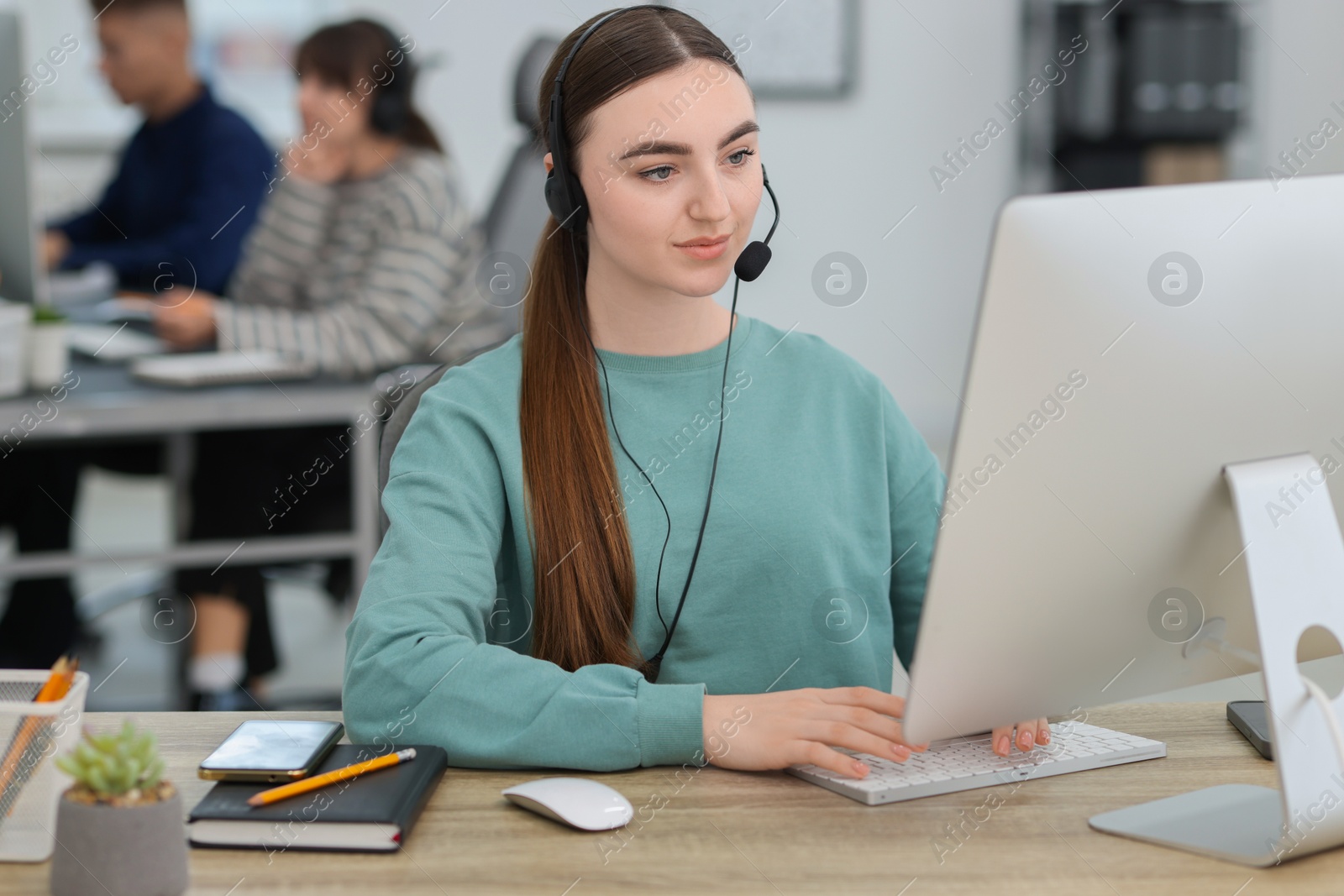 Photo of Saleswoman talking to client via headset at desk in office