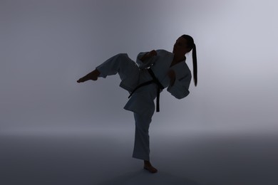 Photo of Silhouette of woman in kimono practicing karate on light background