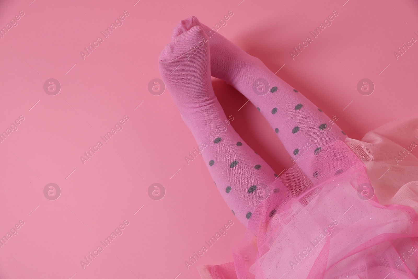 Photo of Child wearing tights on pink background, top view. Space for text