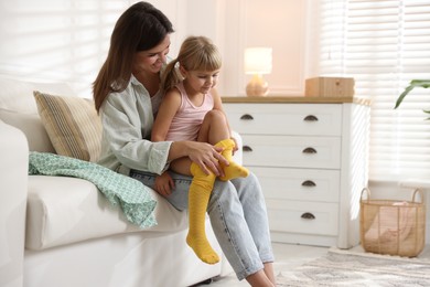 Photo of Mother helping her daughter to put tights on at home. Space for text