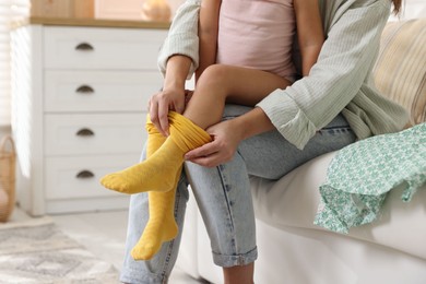 Photo of Mother helping her daughter to put tights on at home, closeup. Space for text