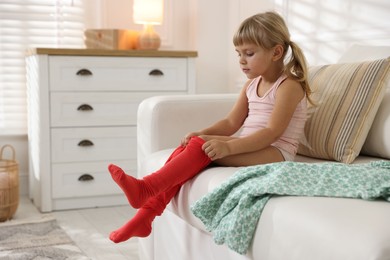 Photo of Little girl putting on soft tights at home. Space for text