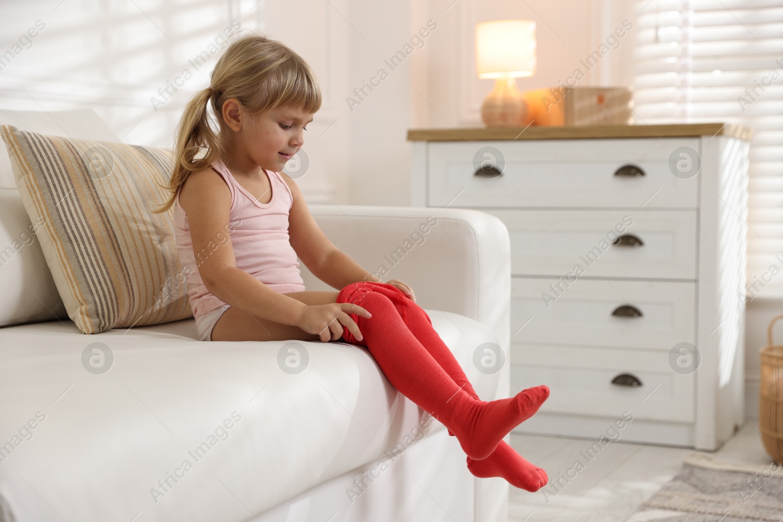 Photo of Little girl putting on soft tights at home. Space for text