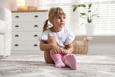 Photo of Little girl putting on soft tights at home