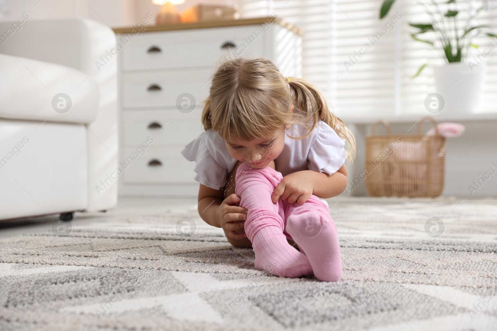 Photo of Little girl putting on soft tights at home