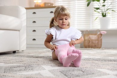 Photo of Little girl putting on soft tights at home