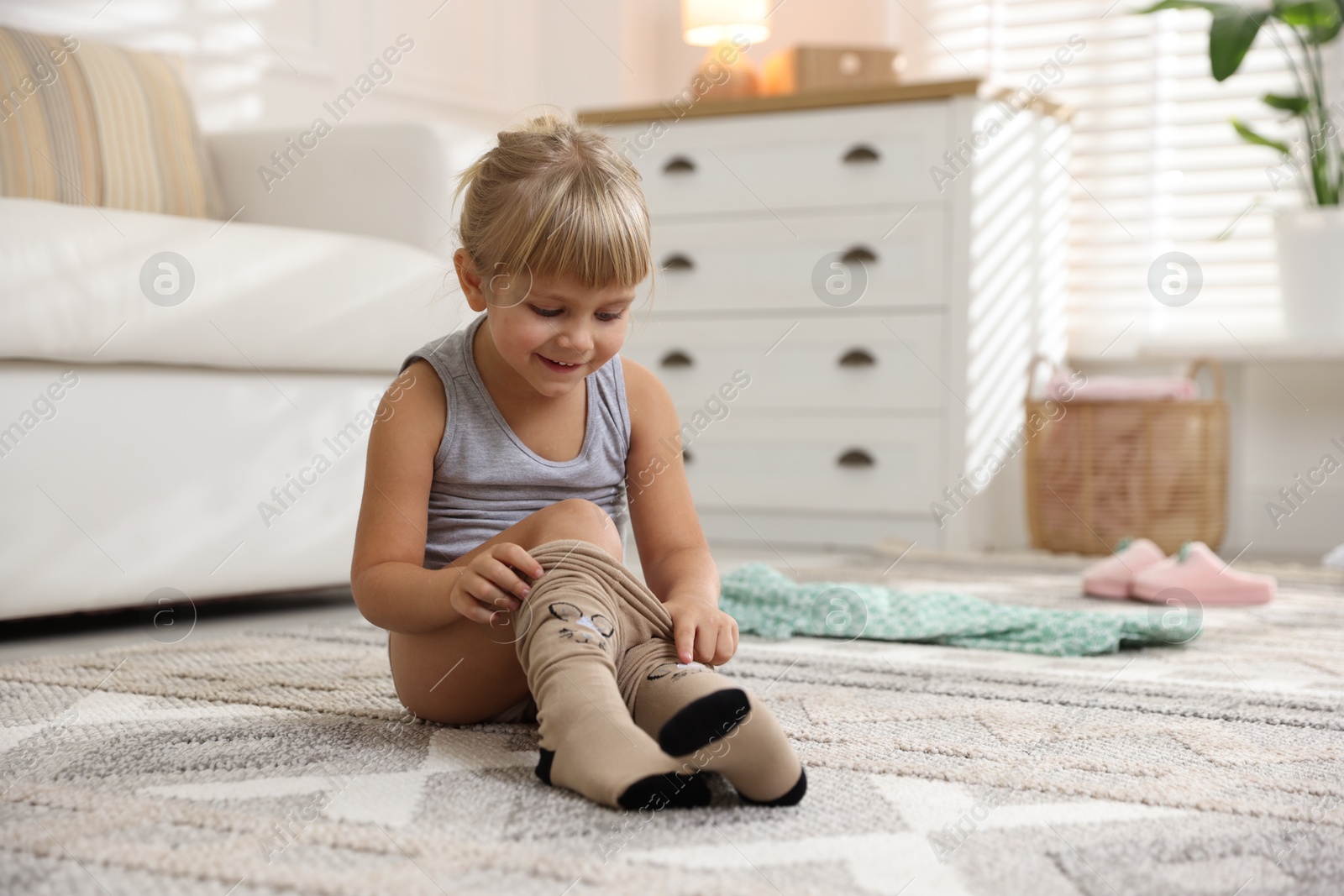 Photo of Little girl putting on soft tights at home. Space for text