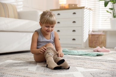 Photo of Little girl putting on soft tights at home. Space for text