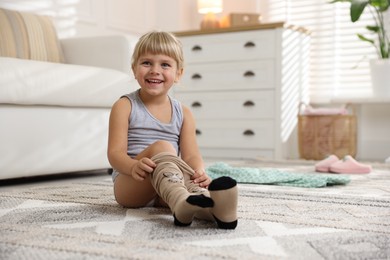 Photo of Little girl putting on soft tights at home. Space for text