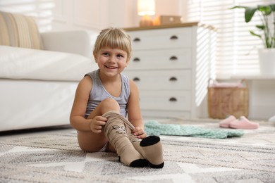 Photo of Little girl putting on soft tights at home. Space for text