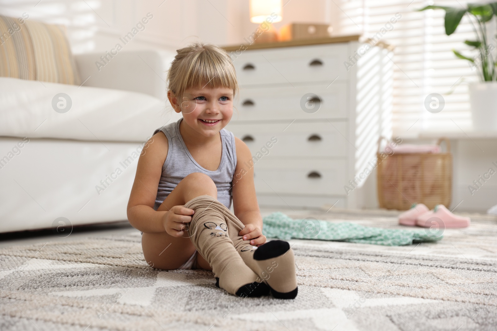 Photo of Little girl putting on soft tights at home. Space for text