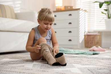 Photo of Little girl putting on soft tights at home. Space for text