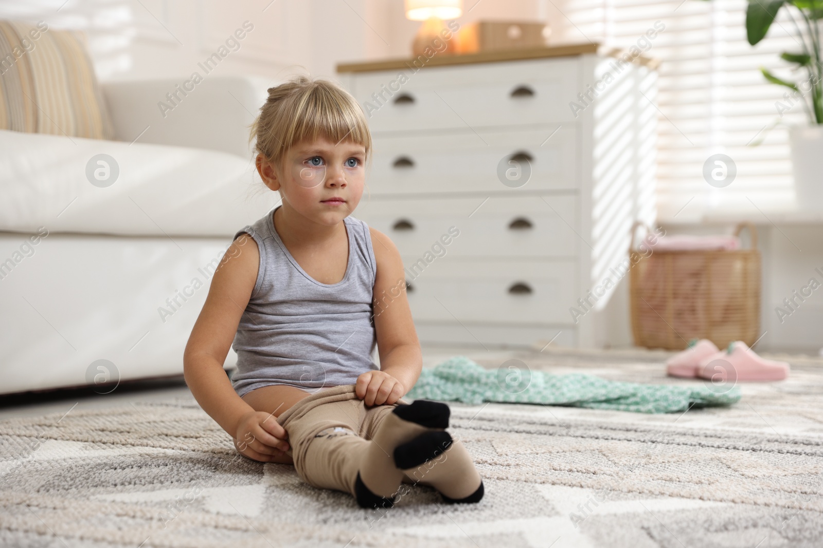 Photo of Little girl putting on soft tights at home. Space for text