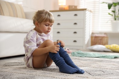 Photo of Little girl putting on soft tights at home. Space for text