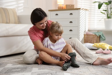 Photo of Mother helping her daughter to put tights on at home