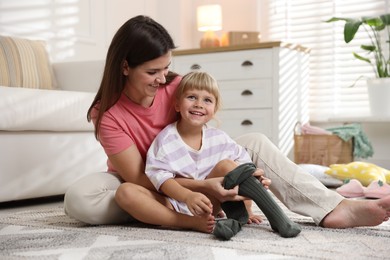 Photo of Mother helping her daughter to put tights on at home