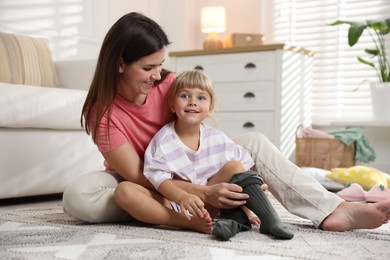 Photo of Mother helping her daughter to put tights on at home