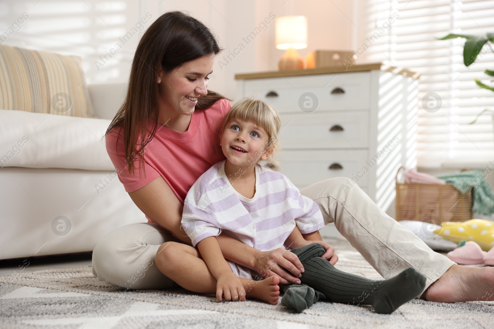 Photo of Mother helping her daughter to put tights on at home