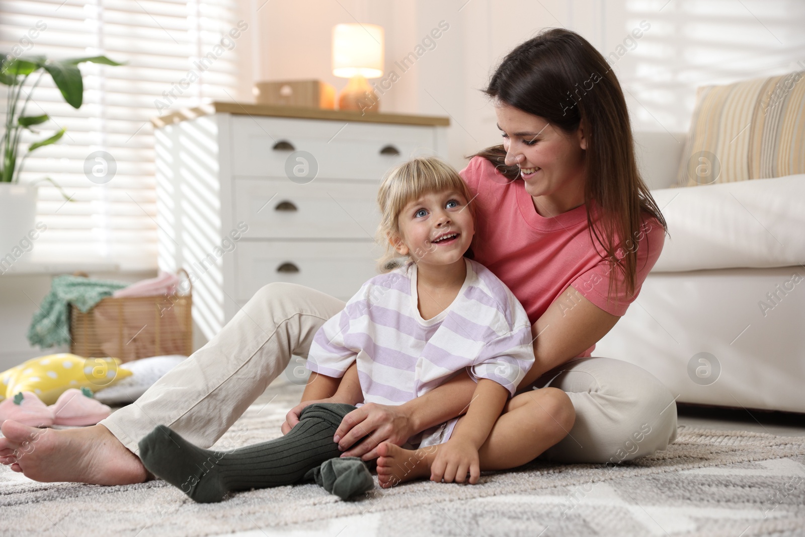 Photo of Mother helping her daughter to put tights on at home