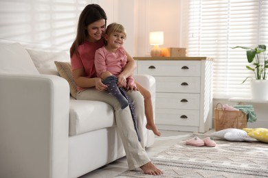 Photo of Mother helping her daughter to put tights on at home. Space for text